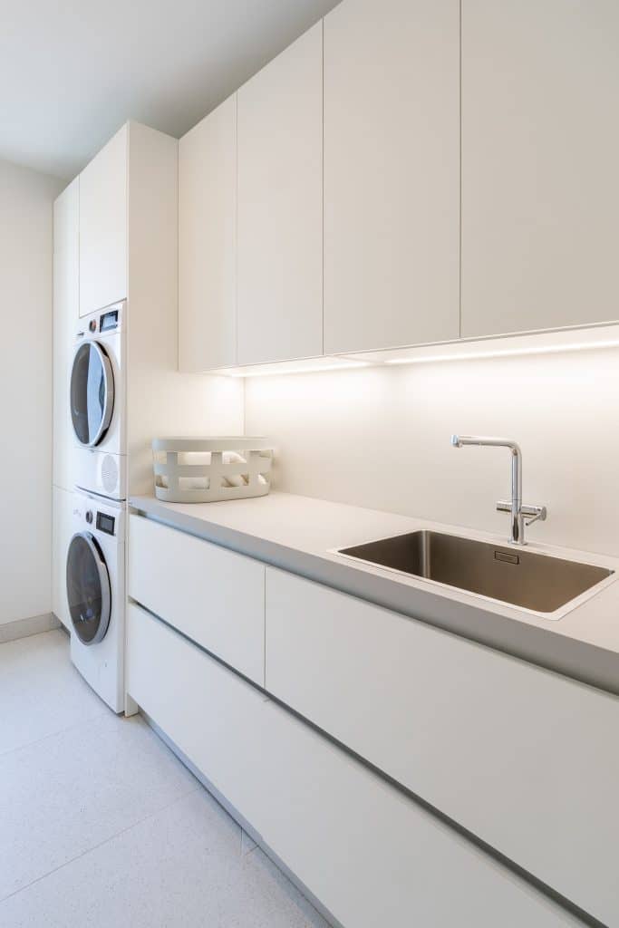Valkoinen kodinhoitohuone pesukoneilla.